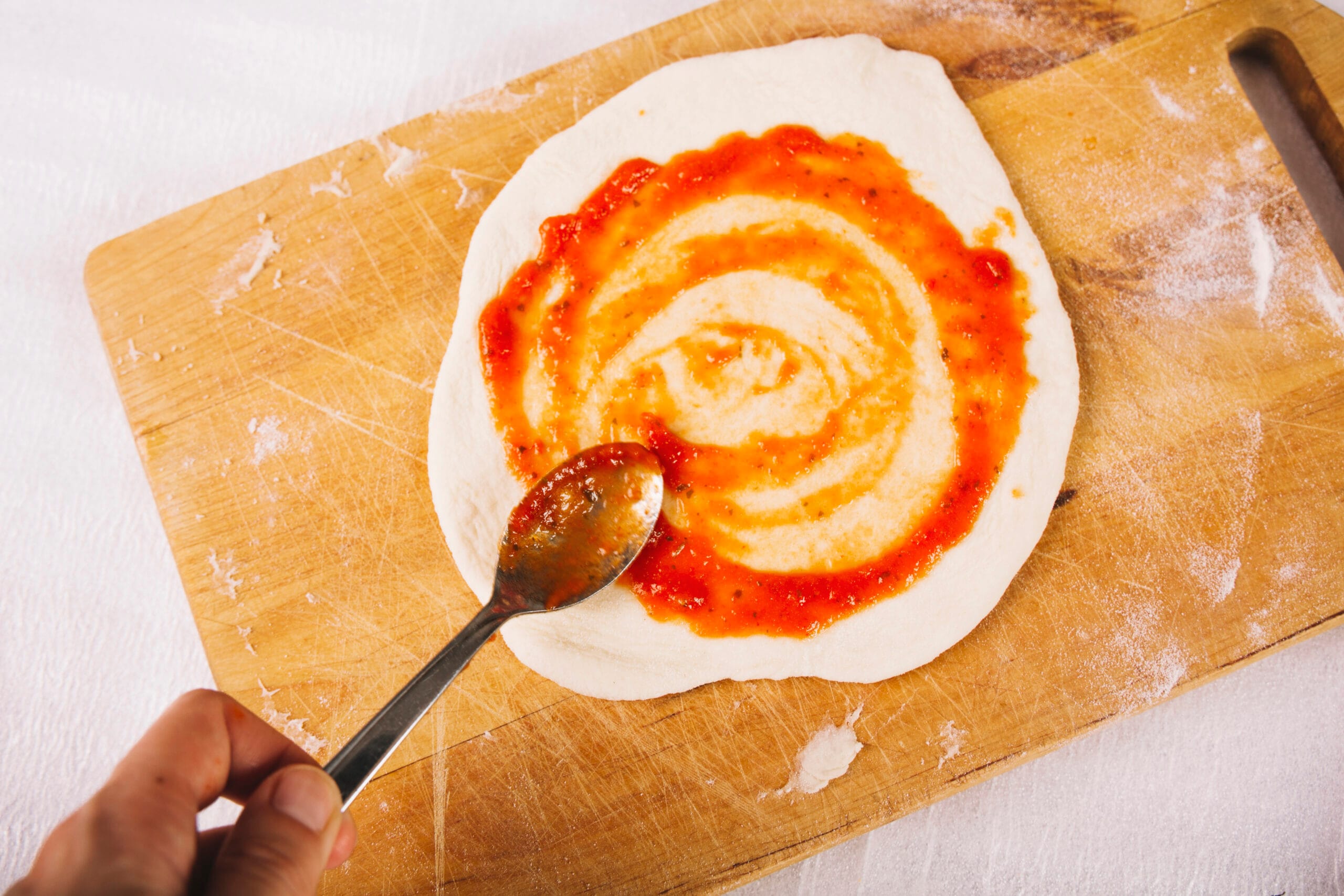 crop hand smearing sauce pizza